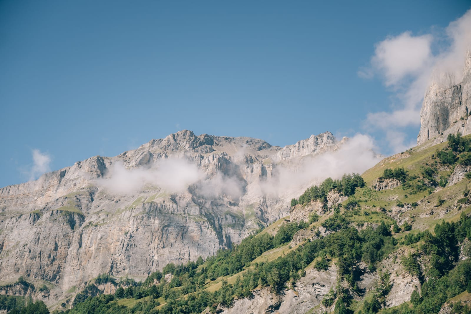 Les parois rocheuses au-dessus de Loèche-les-Bains, quelques nuages accrochés, sous un ciel bleu