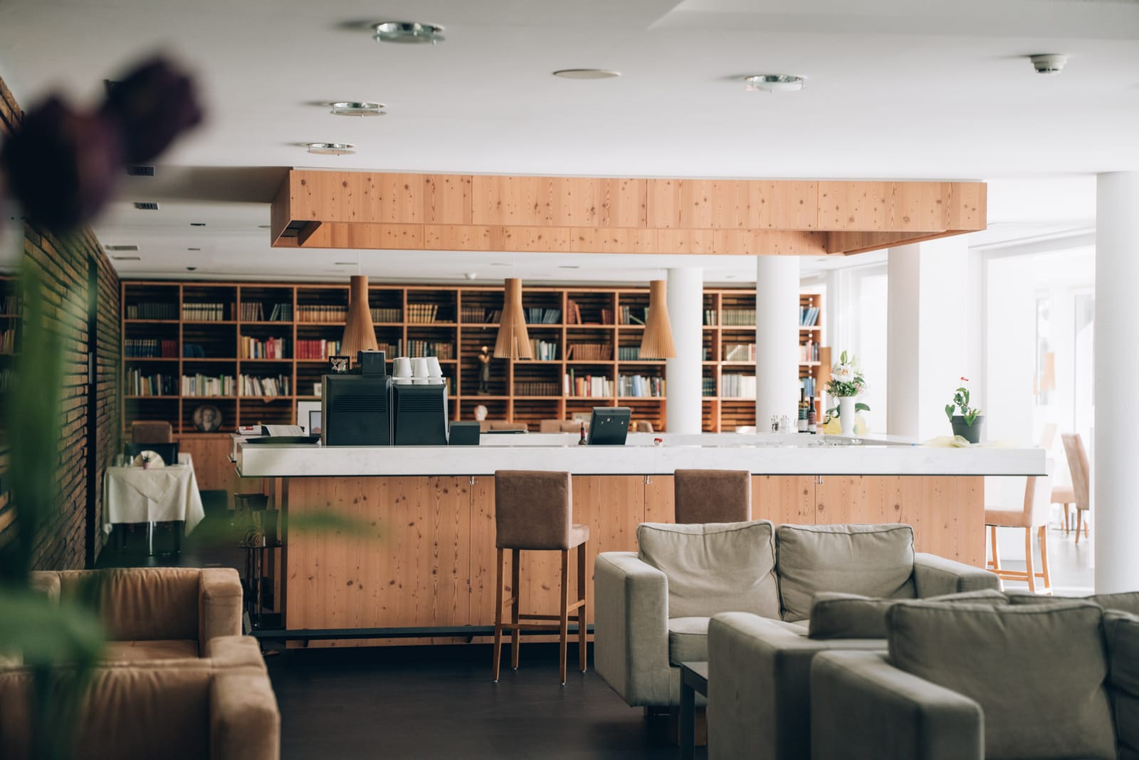 Le salon de la clinique : fauteuils, bar en bois clair et, derrière, un mur de livres